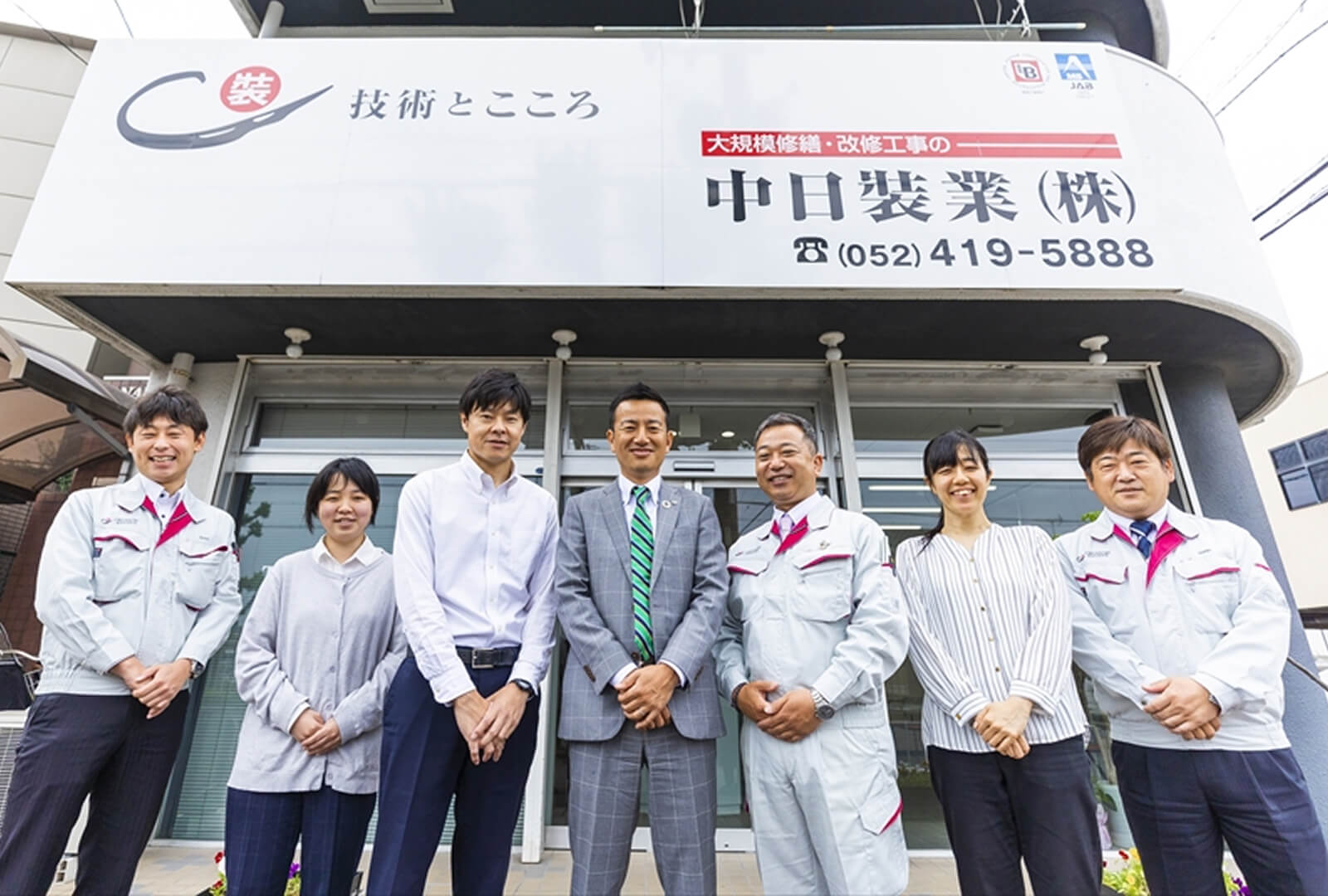 複数のスタッフが中日裝業株式会社店舗の前で、笑顔で並んで立っている集合写真の様子